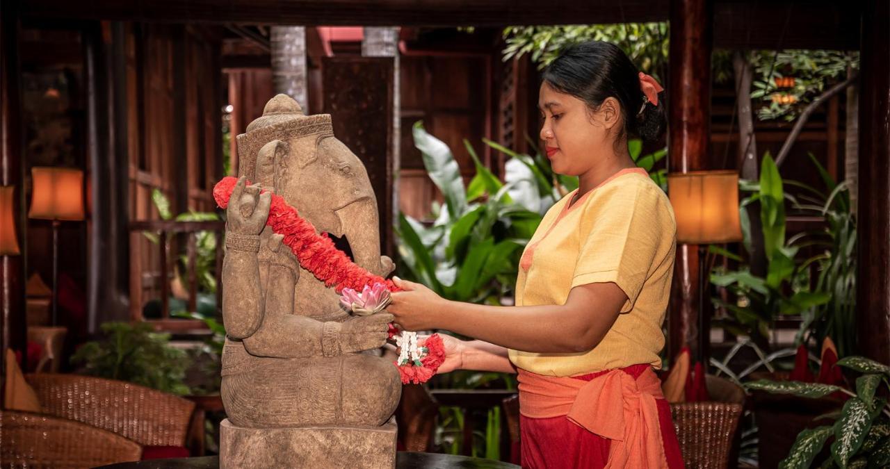Angkor Village Hotel - Small Luxury Hotels Of The World Siem Reap Exteriör bild A woman in Thailand, wearing traditional Thai clothing, garlands a statue of the Hindu god Ganesha.